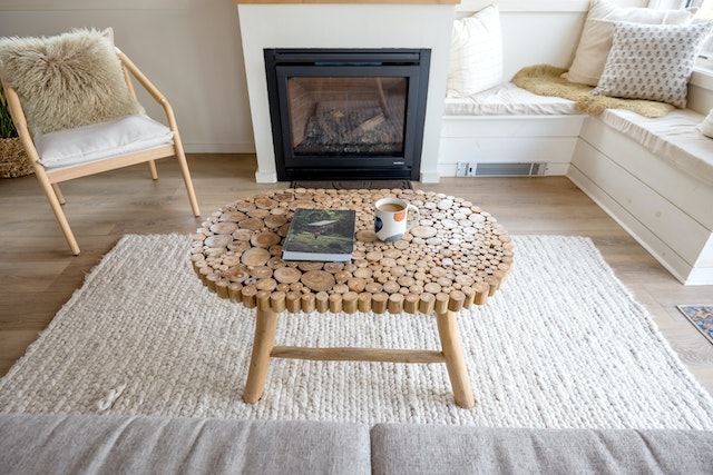 a wooden coffee table on a white rug in front of a fireplace